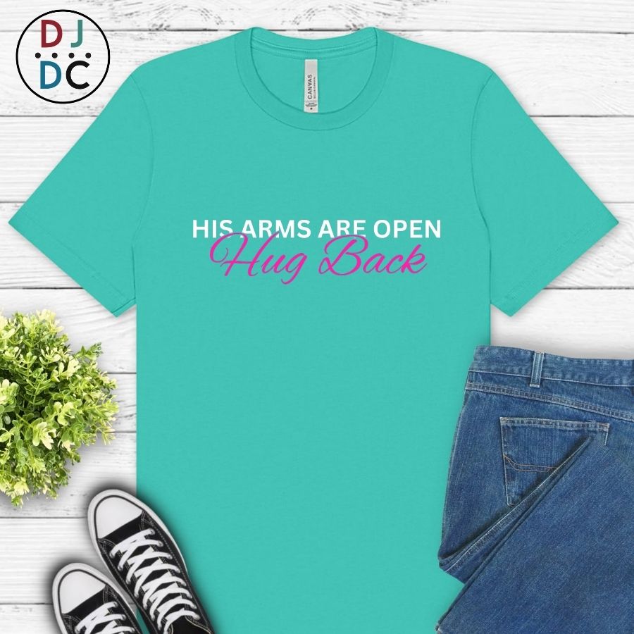 Teal t-shirt with humorous text, paired with jeans and sneakers on a light wooden surface.