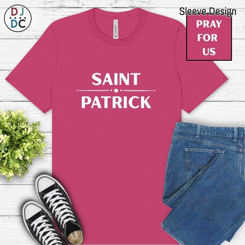 Pink t-shirt with 'Saint Patrick' text, black and white sneakers, blue jeans, and green plant on a wooden surface.