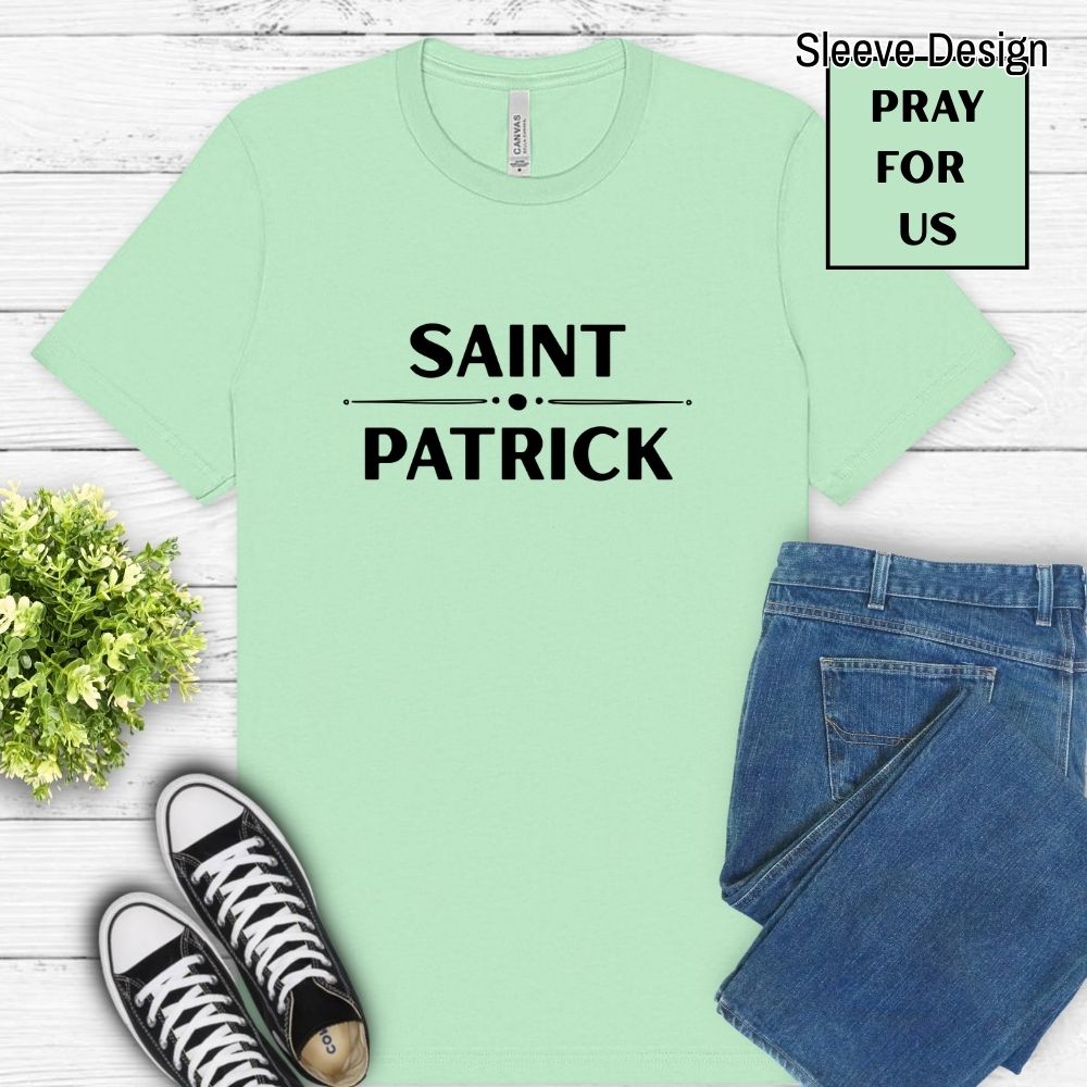 Light green t-shirt with 'SAINT PATRICK' text, paired with jeans and sneakers on a wooden surface.