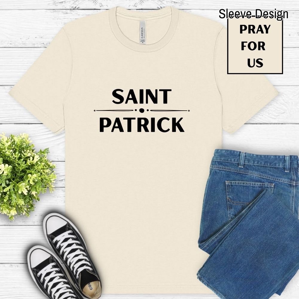 Beige t-shirt with 'Saint Patrick' text, black sneakers, and blue jeans on a wooden surface.